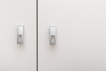 Handles on white wooden swing cabinet. Furniture fittings. Small silver furniture handles