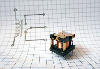 Electromechanical relay in front of the drawn circuit structure.  Electrically operated switch....