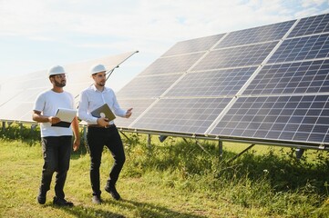 The solar farm, solar panel with two engineers walk to check the operation of the system,...