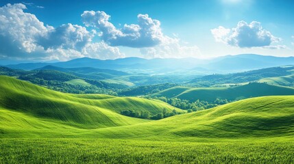 Obraz premium Lush green rolling hills and valleys stretch into the distance under a bright blue sky with fluffy clouds.