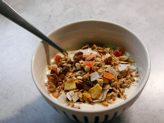 A breakfast bowl filled with yoghurt and home made muesli. Dried fruit, nuts, seeds and oats. Yoghurt parfait.
