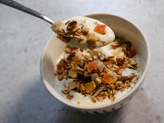 A breakfast bowl filled with yoghurt and home made muesli. Dried fruit, nuts, seeds and oats. Yoghurt parfait.