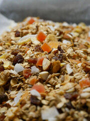 A breakfast bowl filled with yoghurt and home made muesli. Dried fruit, nuts, seeds and oats. Yoghurt parfait. A spoon in the yoghurt.