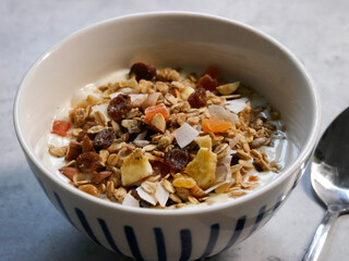 Breakfast bowl with yoghurt and muesli in it. A spoon in  it. Breakfast food. home made.
