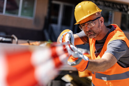 A construction worker secures a safety barrier tape on a sunny day
