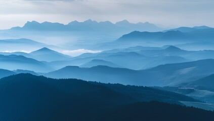 Rolling blue hills create a serene atmosphere as morning mist gently blankets the landscape, highlighting distant mountain silhouettes