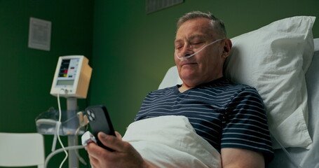 Senior patient, holding the phone, participates in virtual activities like online puzzles or games...
