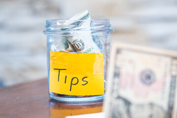 Tip Jar Filled with Dollar Bills - Concept of Tipping