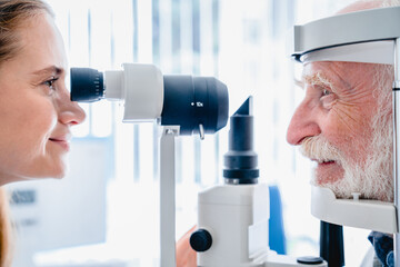 Female oculist checking senior male patient vision. Close up photo