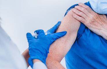 Cropped photo of an elderly patient`s arm with injection. Close up picture of doctor`s hands making injection