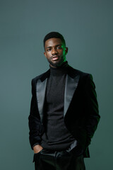 Confident black man in sophisticated black turtleneck and suit striking a powerful pose for the camera