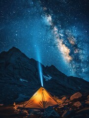 A glowing tent under a starry sky illuminates the majestic mountains, showcasing the beauty of nature and the universe.
