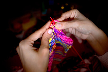 Closeup of hands knitting a multicolored scarf