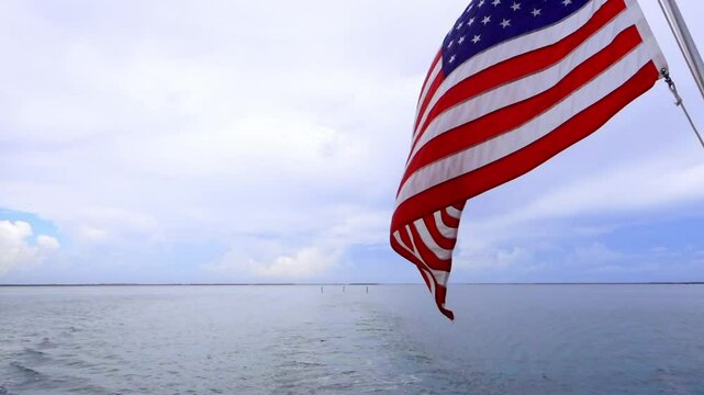 American flag waving over the water from the back of a boat