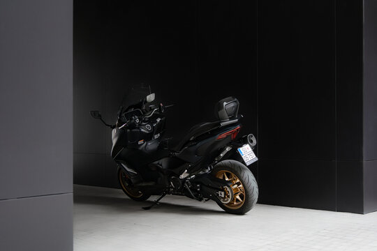 Rear view of Yamaha TMAX Tech 560cc MAX scooter in a sleek, modern black garage setting. The black and gold color scheme highlights its sporty and premium design - 05.06.2024 Subotica, Serbia