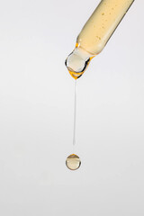 Pipette with serum, gel, oil or other cosmetic product with falling drop. Macro closeup