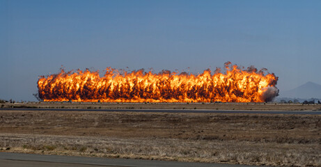 A dramatic image of a row of fire created by a munitions explosion with against a blue sky