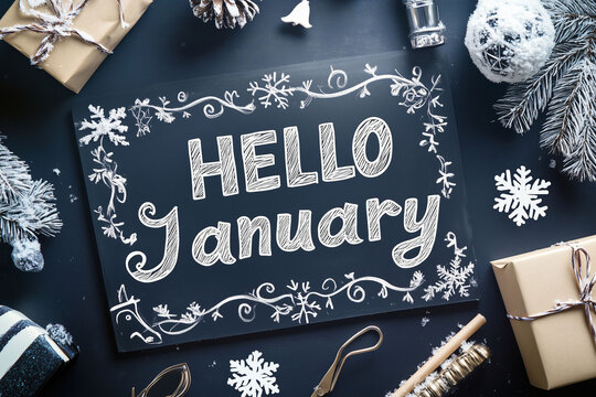 Januar Illustration "Hello January" mit Dekoration aus Winterdeko, Schneeflocken und Geschenken, Kreide Schriftzug auf Schiefertafel mit Winter Deko