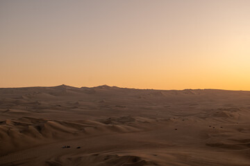 Naklejka premium Immense and Dramatic Dune Landscape with Various Buggies Riding by Huacachina in Ica, Peru at Sunset