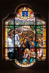 A priest distributing Communion to the faithful. A stained-glass window in the Basilica of Our Lady...