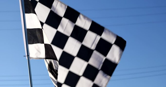 Checkered racing flag blows in the wind at a race car track finish line