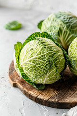 Fototapeta premium Fresh savoy cabbage on wooden cutting board on white background, vertical image