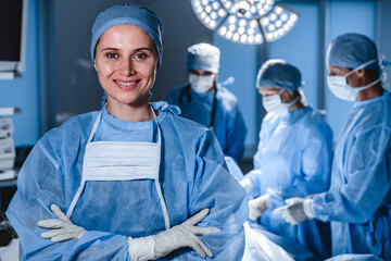 Portrait of smiling female surgeon with operation in background.
