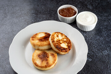 Cottage Cheese Pancakes with Cream and Jam on a Rustic Surface