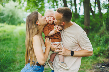 Mom, dad and little son on a walk in the park. Concept of parent time with child. Happy family couple with child in nature.