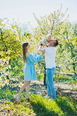 A young married couple, a man, a woman and a little son, are walking in the park. Time for a walk, mom, dad and small child.