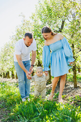 A young married couple, a man, a woman and a little son, are walking in the park. Time for a walk, mom, dad and small child.