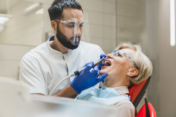 Arabian stomatologist dentist checking curing healing operating filling female patient`s teeth...