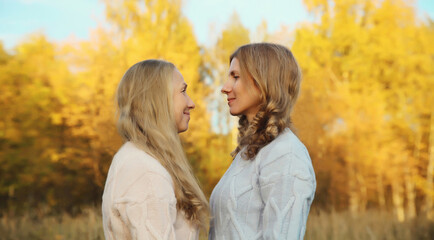 Fototapeta premium Happy two women, smiling mature mother and adult daughter hugging in autumn park