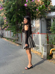 Brunette, beautiful, young girl smiling with a happy expression. Girl posing from the side and full length outdoors, on a street. Flirty, cute playful girl