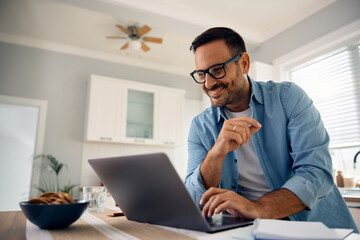 Happy man surfing  net on laptop at home.