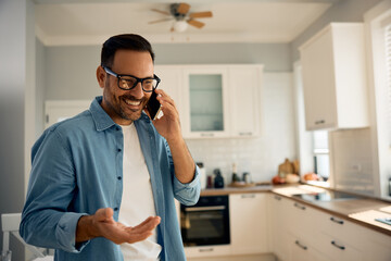 Happy man making  phone call in kitchen.