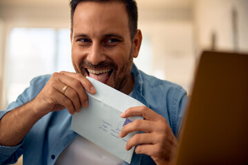 Happy man licking envelope at home.