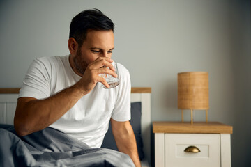 Mid adult man drinking water after waking up in morning.