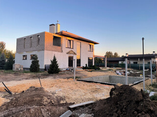 A house is being built in the countryside, featuring a partially completed structure on a plot with...