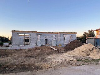 A house is being built in the countryside, featuring a partially completed structure on a plot with...
