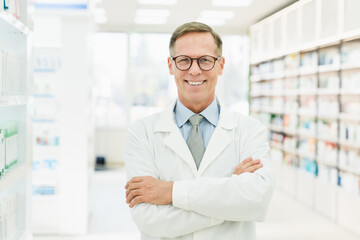 Smiling male caucasian middle-aged mature confident pharmacist druggist in white medical coat standing with arms crossed in pharmacy drugstore