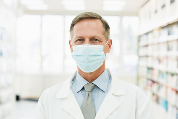 Pandemic situation concept. Doctor pharmacist chemist druggist looking at the camera in protective face mask against Coronavirus standing in pharmacy