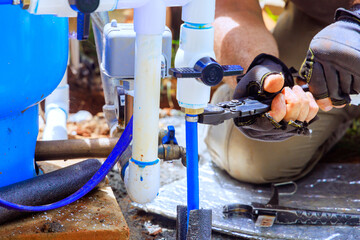 Plumber assembles connection of water well to water system at house