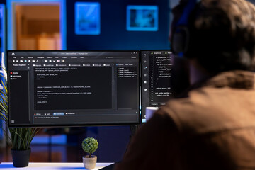 Man doing software quality assurance, reading source code on computer screen before implementing...