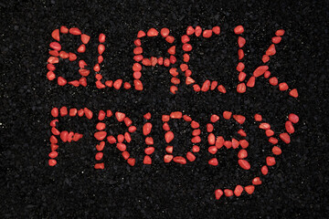 Black Friday words made with small red stones, on a background of black stones.