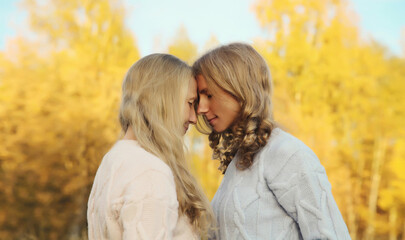 Fototapeta premium Happy two women, smiling mature mother and adult daughter hugging in autumn park