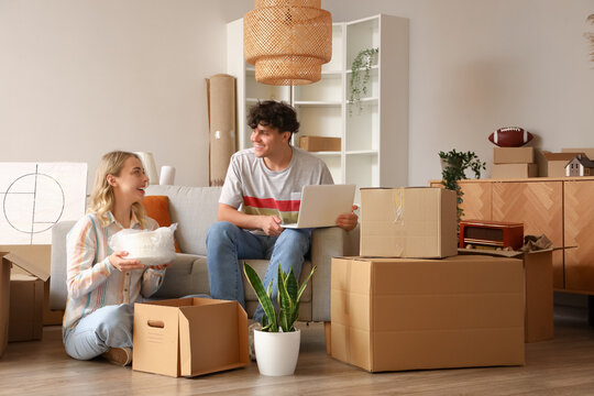 Young couple using laptop in room on moving day