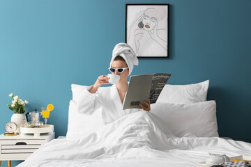 Morning of young woman with magazine drinking coffee in bedroom