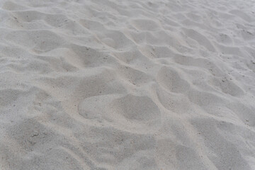 Background with beach sea sand texture. An image of the sandy surface with natural patterns and lines created by the wind and footsteps of tourists.