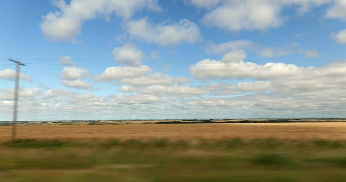 Driving plate side view on a highway through open plains and farmland in Midwestern United States agricultural fields under a wide sky rural travel and American heartland concept